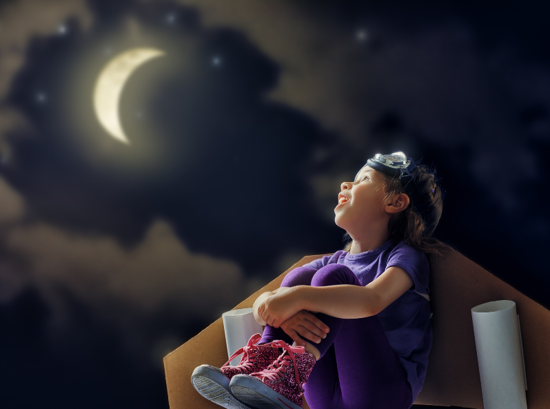 Dziewczynka z latarką na głowie patrząca w nocne niebo z księżycem